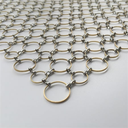 A piece of decorative mesh made of brass rings and aluminum fasteners.