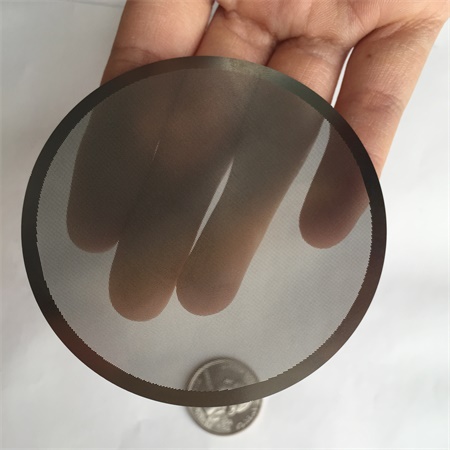 A hand is holding a piece of etched filter plate.