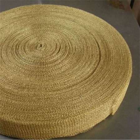 A roll of knitted brass mesh on the ground.