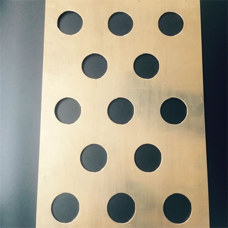 A piece of perforated brass mesh panel on the black ground.