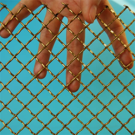 A hand is hold a piece of crimped brass mesh.