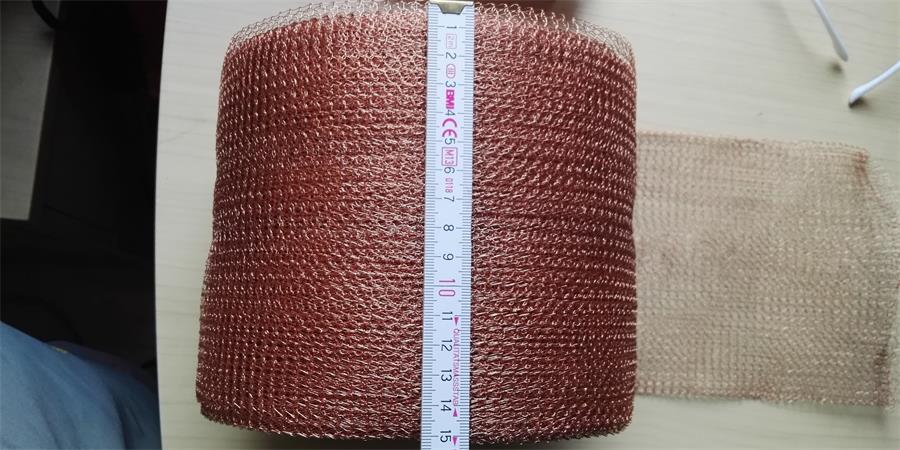 A tape measure is measuring the width of the knitted copper mesh roll.